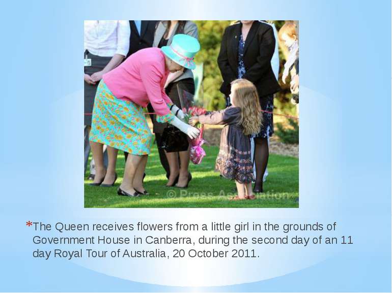 The Queen receives flowers from a little girl in the grounds of Government Ho...