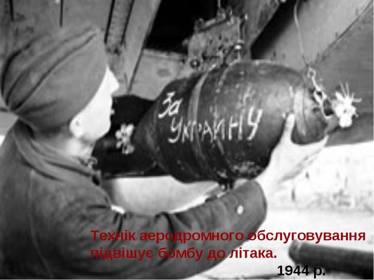 Технік аеродромного обслуговування підвішує бомбу до літака. 1944 р. 21